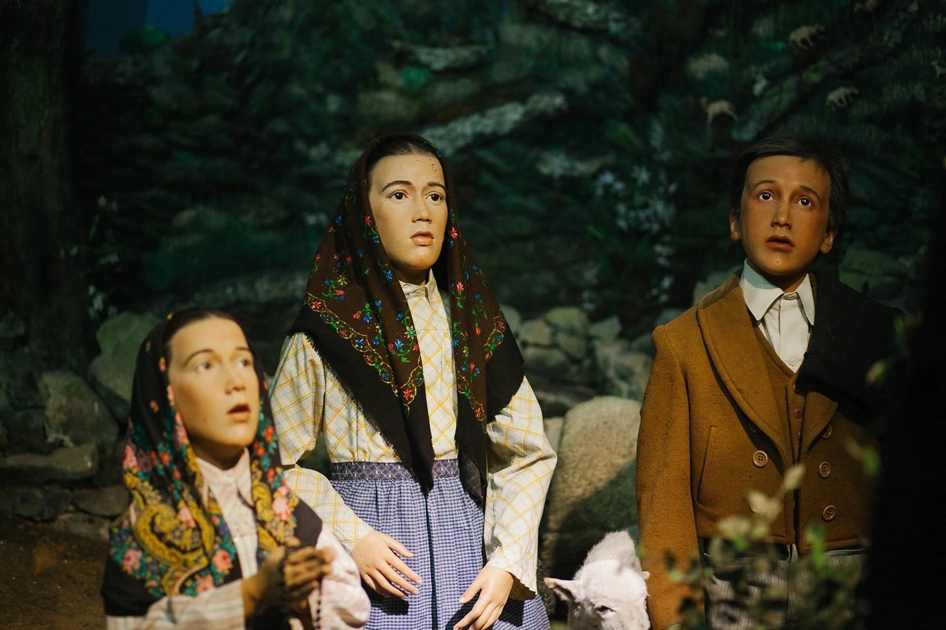 Wax figures of two children and a man in traditional dress