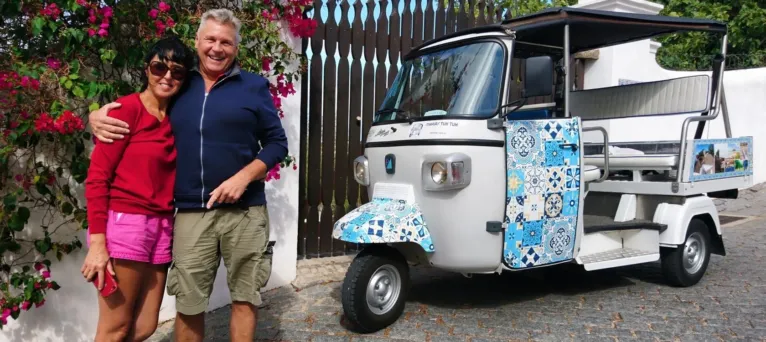 Couple smiling beside a tile-decorated tuk-tuk