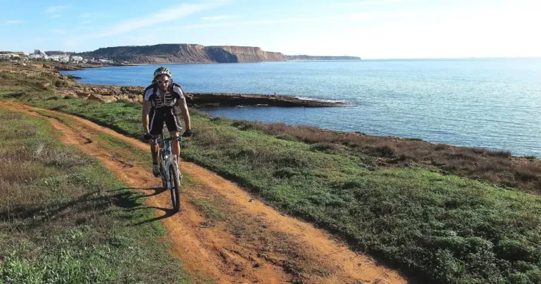 Mountain biker on a dirt track above a rocky coastline
