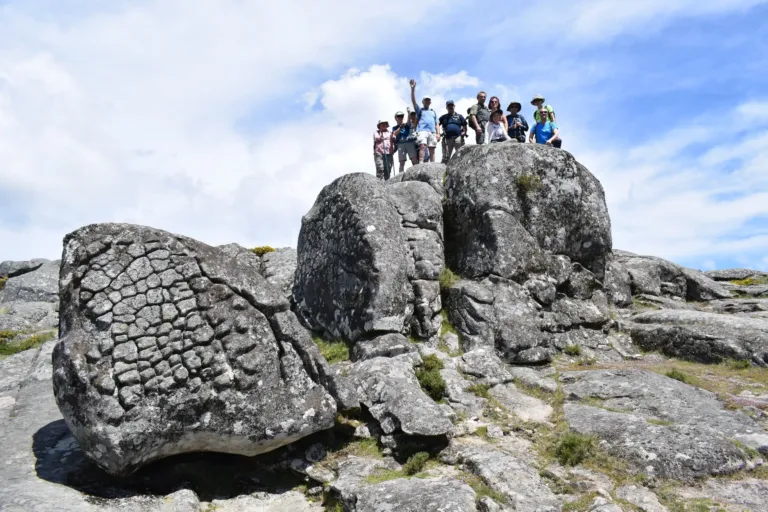 Group of hikers standing on huge granite boulders on a hilltop