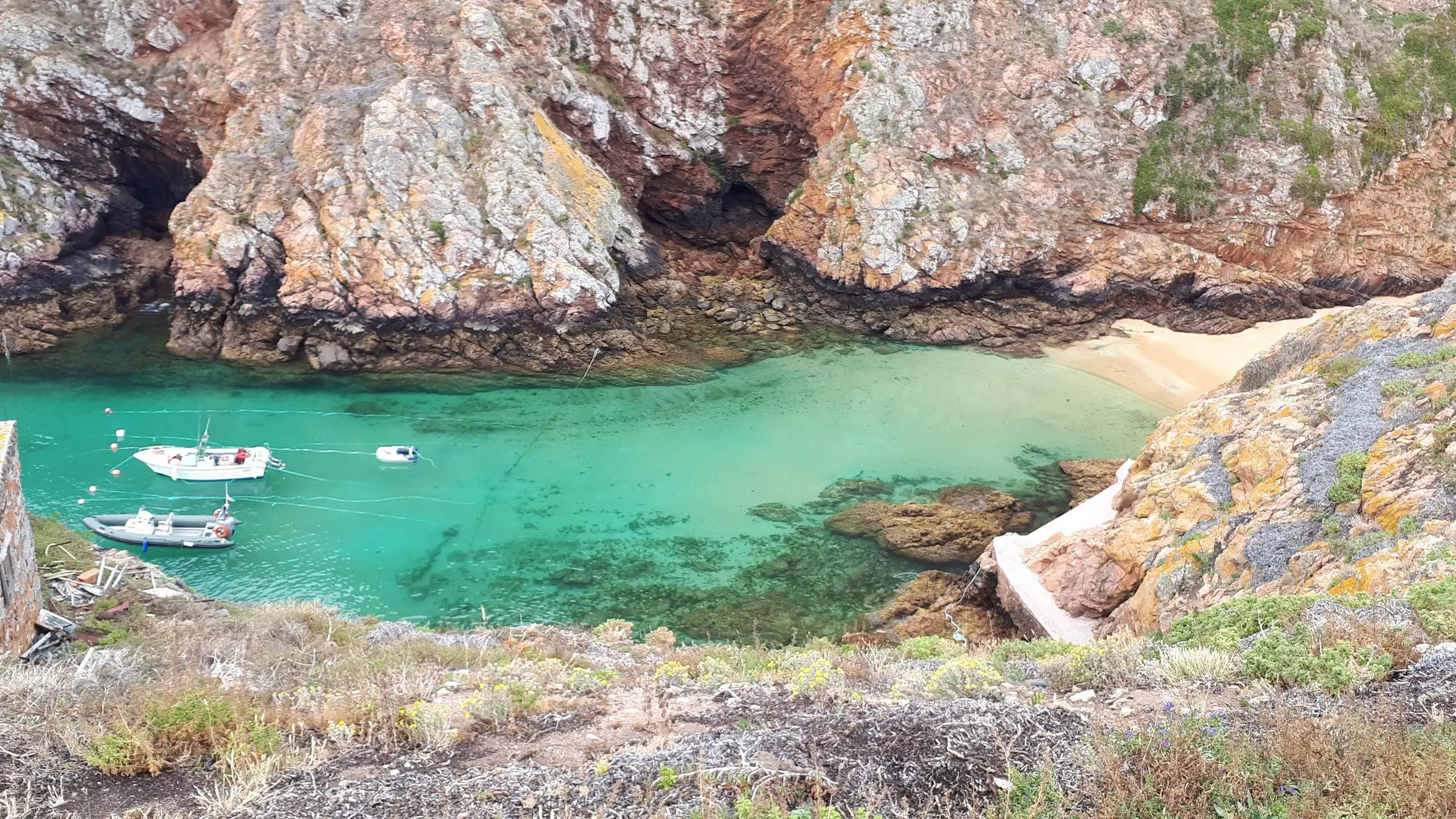Turquoise cove with moored boats below rocky cliffs