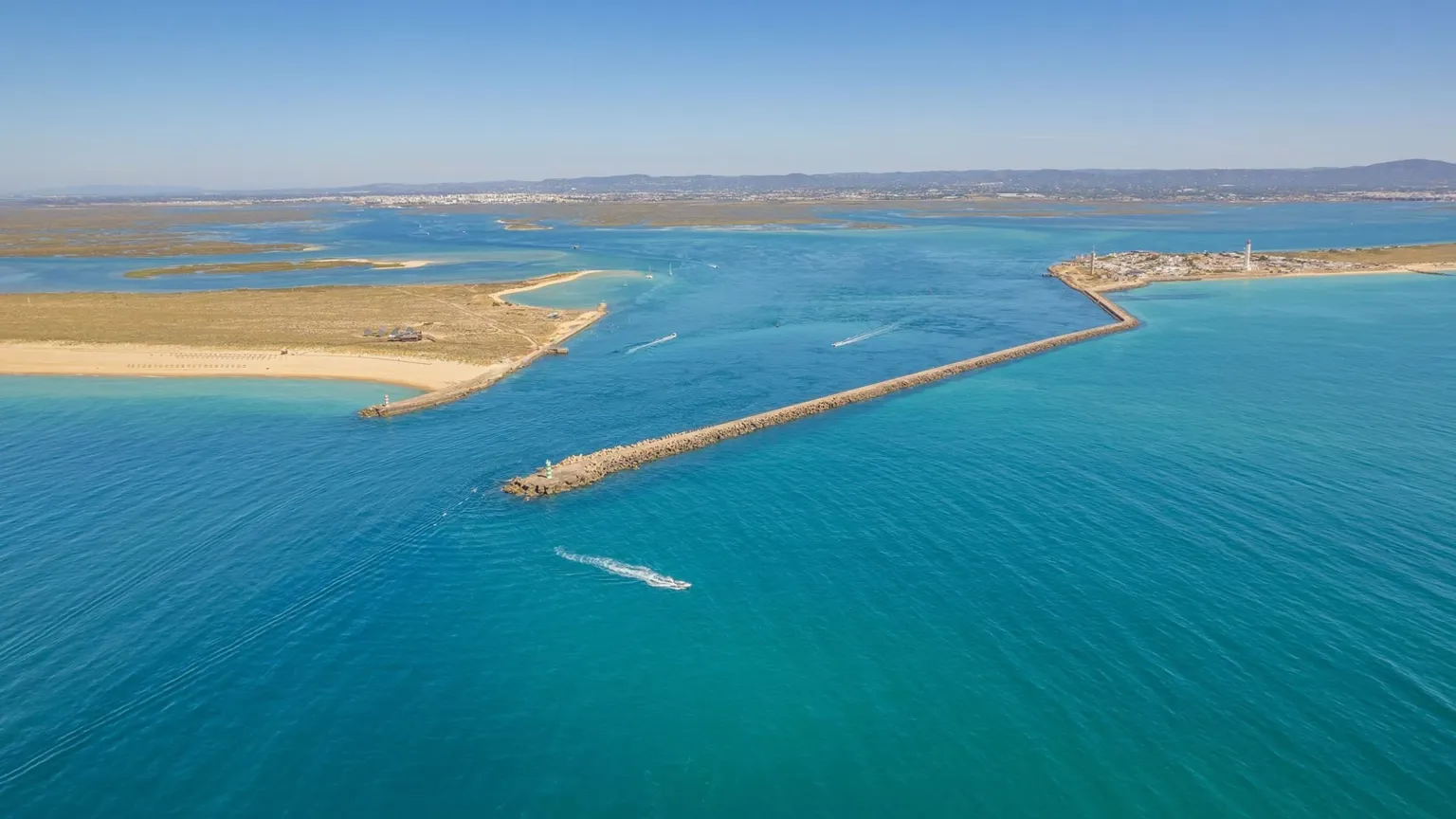 Aerial view of a channel with breakwaters at the mouth of a lagoon
