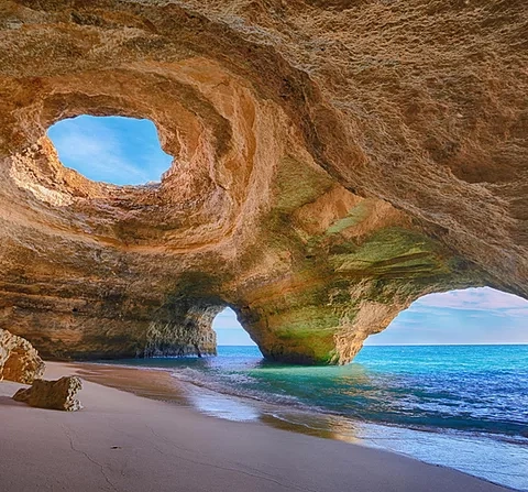 Sea cave with a round skylight, a sandy beach and sea views
