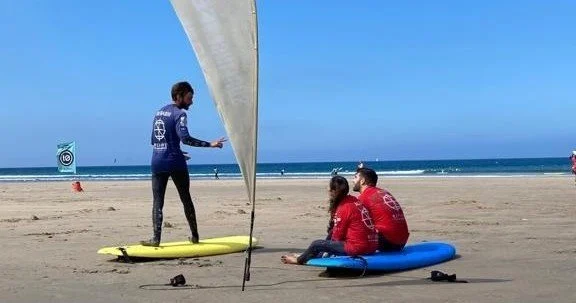 Surf student and instructors on a beach beside yellow and blue boards
