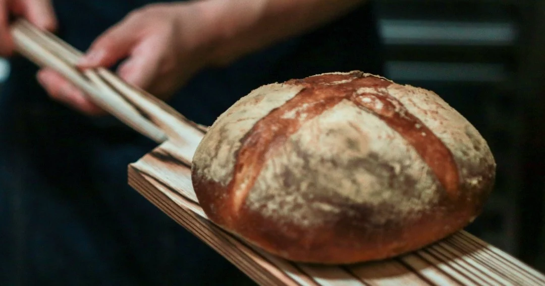 Rustic loaf of bread on a wooden peel