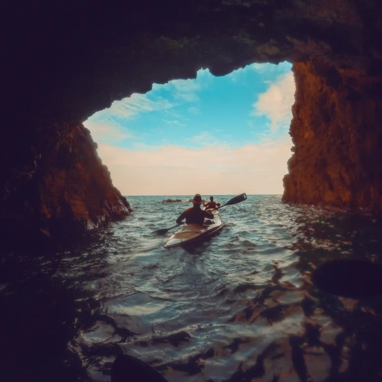 Kayaker silhouetted in a sea cave opening looking out to sea