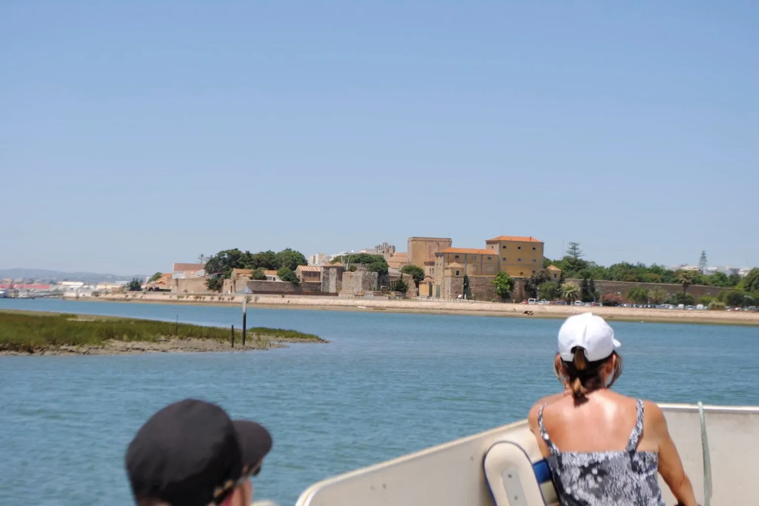 Passengers on a boat approaching a low town on the shore
