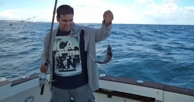 Man holding a fishing rod and a fish aboard a boat