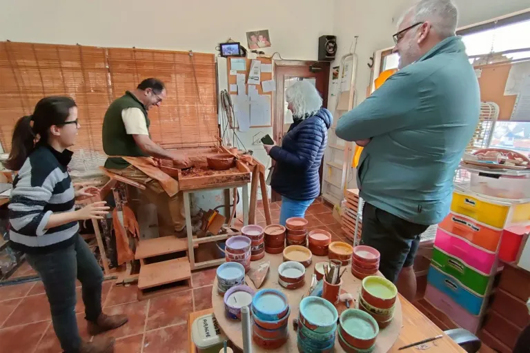 Visitors watching a craftsman at work in a clay workshop