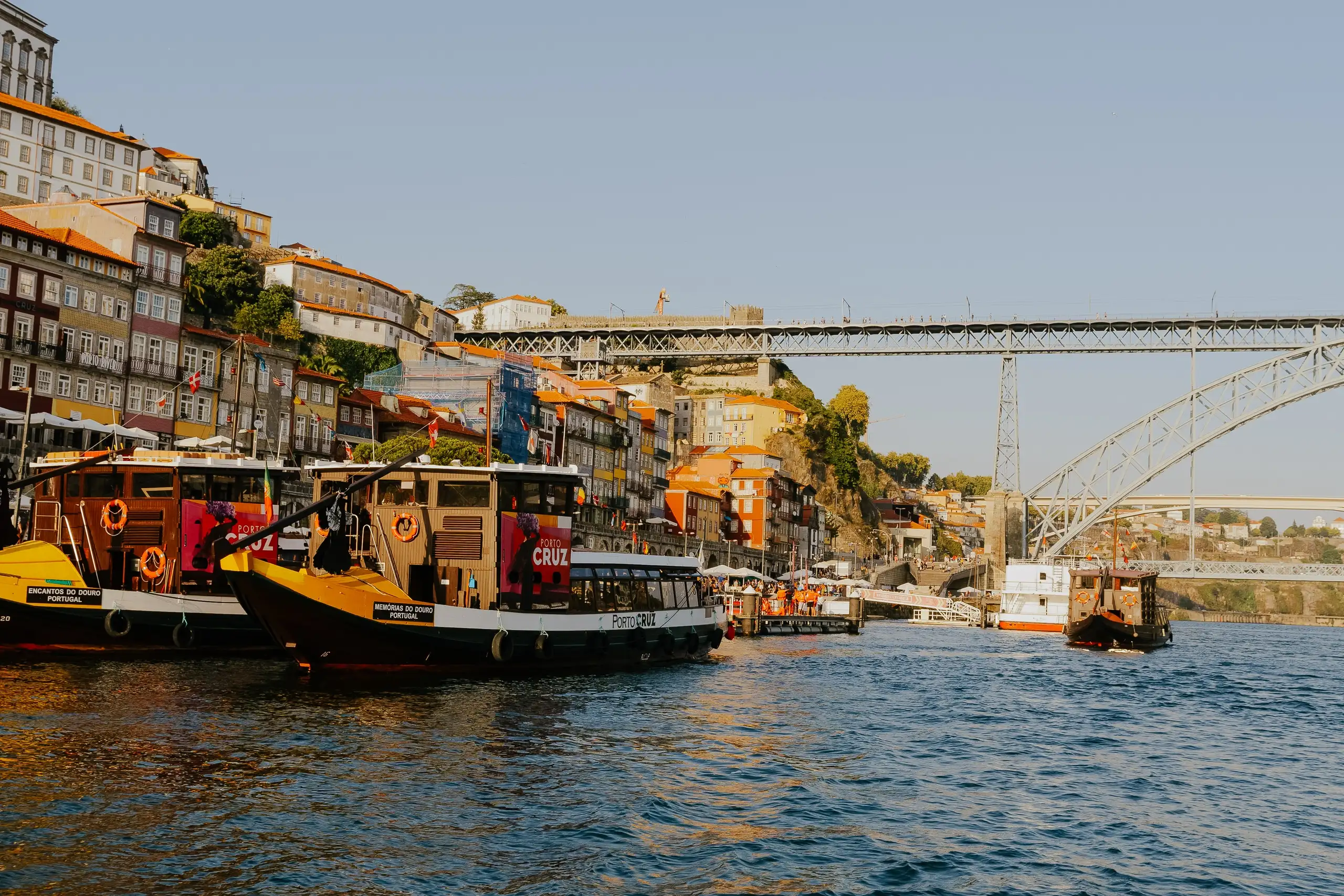 Traditional boats on the river in front of a riverside city with an iron bridge