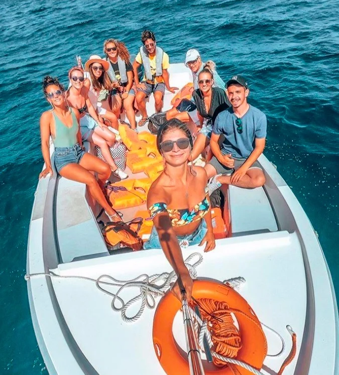 Group of friends smiling on a small boat, seen from above