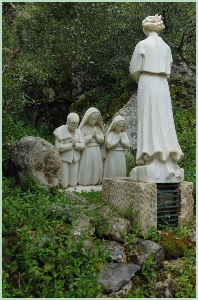 White stone statues of a standing woman and three children among trees