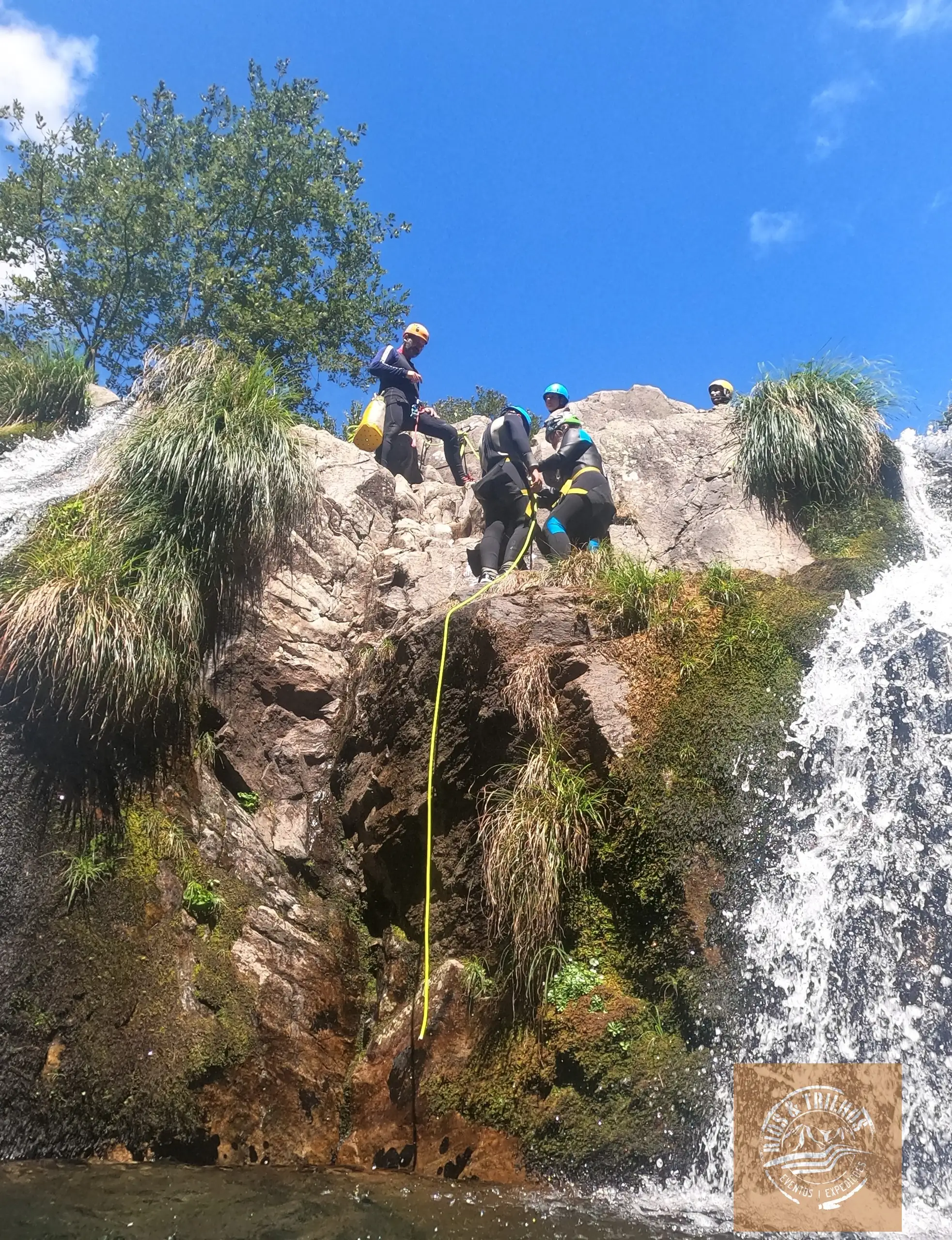 Canyoners descending a rocky waterfall slope