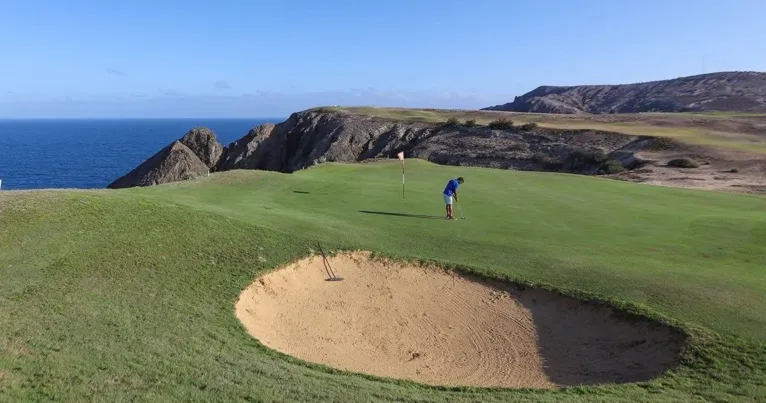 Golf green and sand bunker on a clifftop course above the sea
