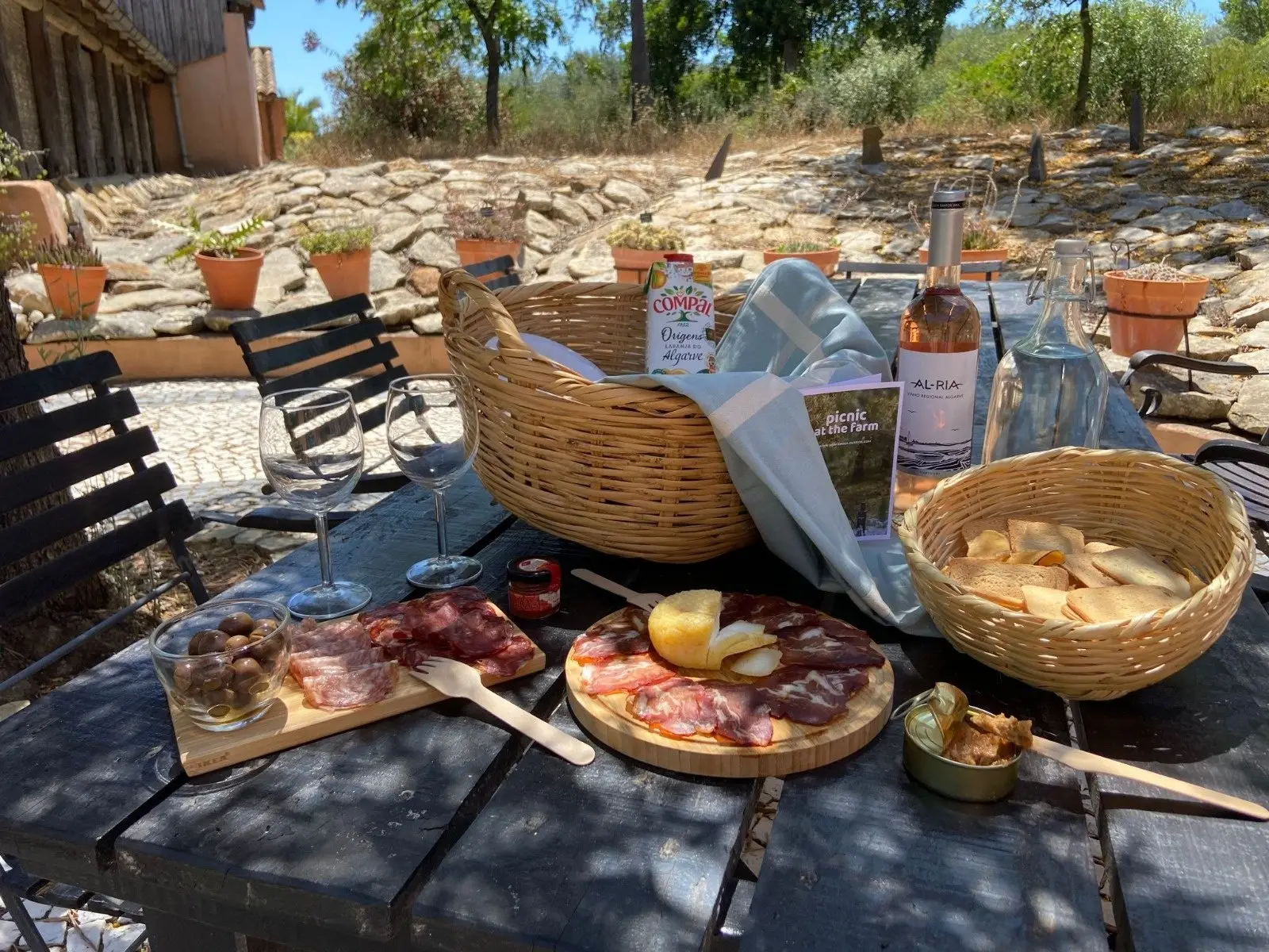 Picnic on a table with a basket, cured meats, cheese and bottles