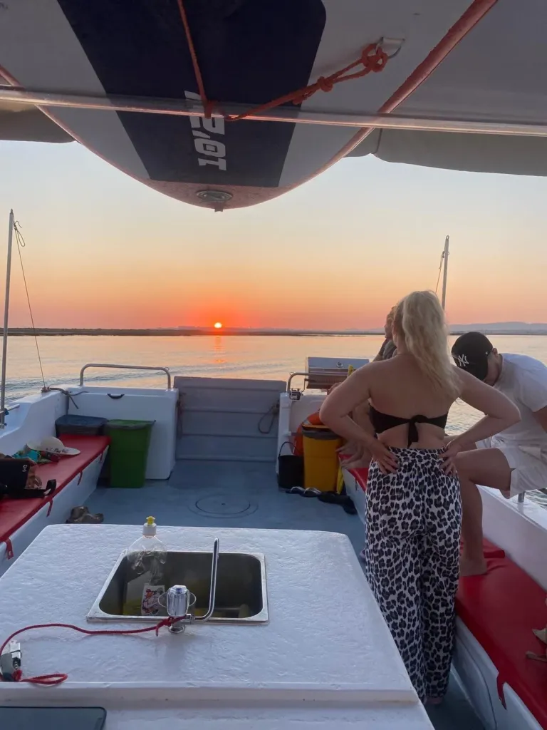 Woman on a boat deck watching the sun set over a lagoon
